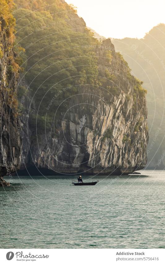 Serene boat ride in the majestic Ha Long Bay, Vietnam vietnam ha long bay water limestone cliff sunlight serene fisherman navigation solitary travel tourism