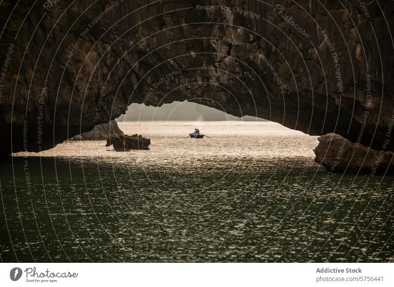 Serene boat ride in Halong Bay under limestone arch halong bay vietnam fisherman water serene tranquil traditional natural fishing landscape seascape travel