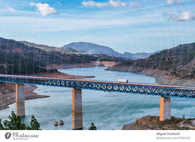 Truck with refrigerated semi-trailer driving along a viaduct over a swamp, landscape. truck transport bridge rules granada andalusia reservoir refrigerator