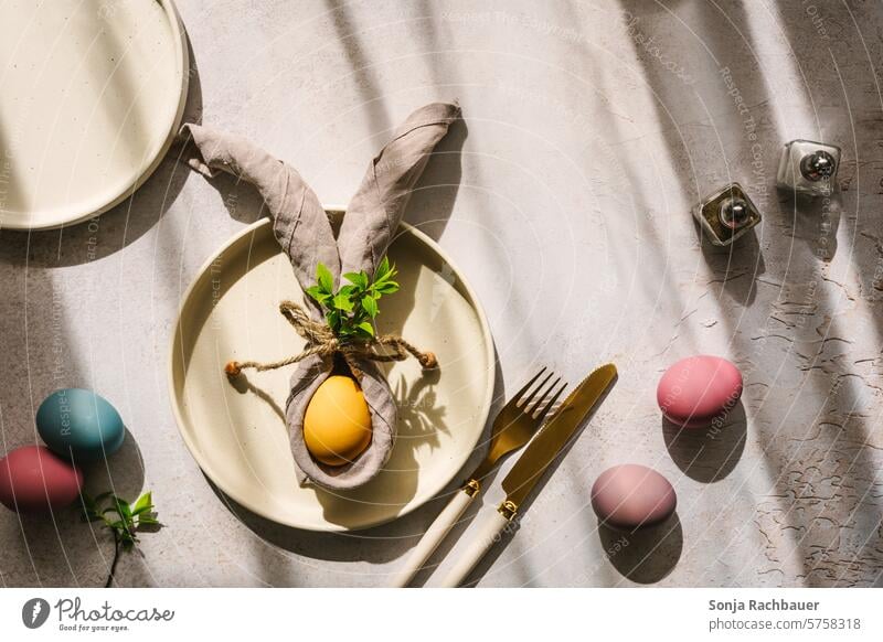 A yellow Easter egg with bunny ears from a napkin on a plate. Top view. Hare ears Napkin Easter Bunny Spring Colour photo hard light Drop shadow Table Plate