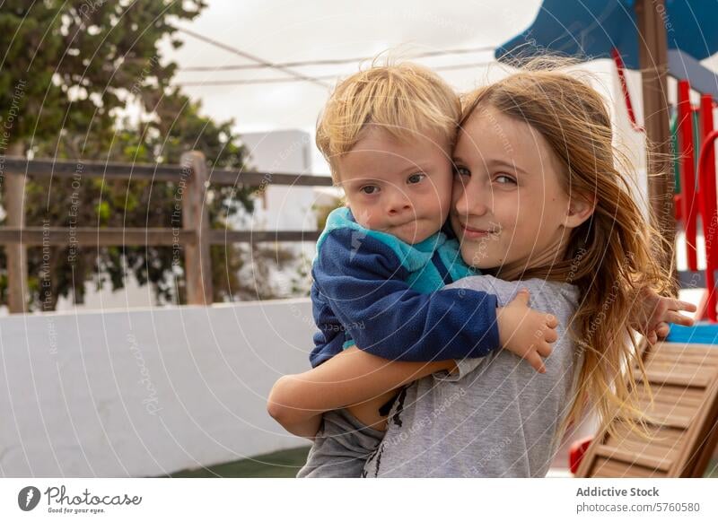 Sibling love at the playground with a Down syndrome toddler baby down syndrome boy girl child brother sister affection inclusion diversity hug embrace care