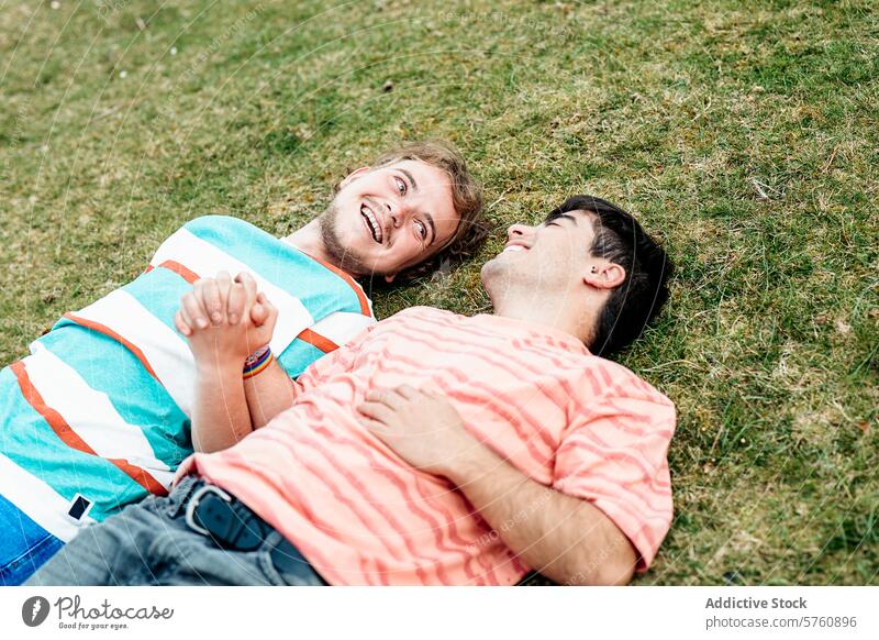 Two men, deeply in love and both transgender, enjoy each other's company, smiling and holding hands on a grassy field couple gay happiness joyful togetherness