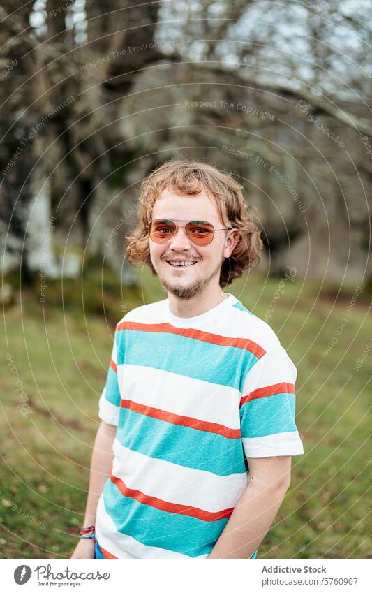 A man with a warm smile stands outdoors, his casual style and carefree spirit embodying the joy of a day spent in nature portrait sunglasses cheerful happy