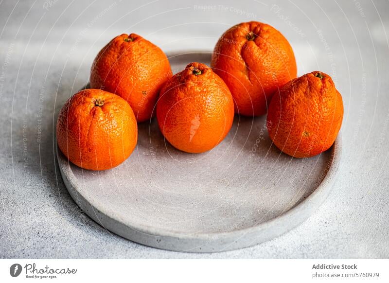 Fresh Clementines on a Concrete Plate clementine citrus fruit ripe orange concrete plate round close-up fresh arrangement grey background juicy healthy snack