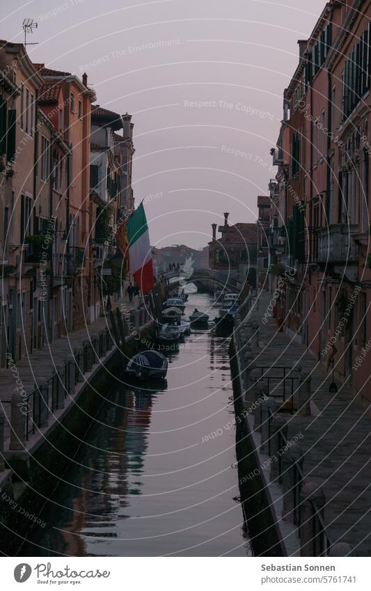 Typical narrow canal surrounded by buildings with boats during evening twilight, Venice, Veneto, Italy venice travel town italian famous attraction historic