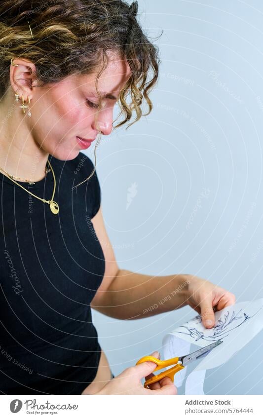 Woman carefully cutting paper design in studio woman scissors focus curly hair crafting art artist creativity precision concentration jewelry manual skill hobby