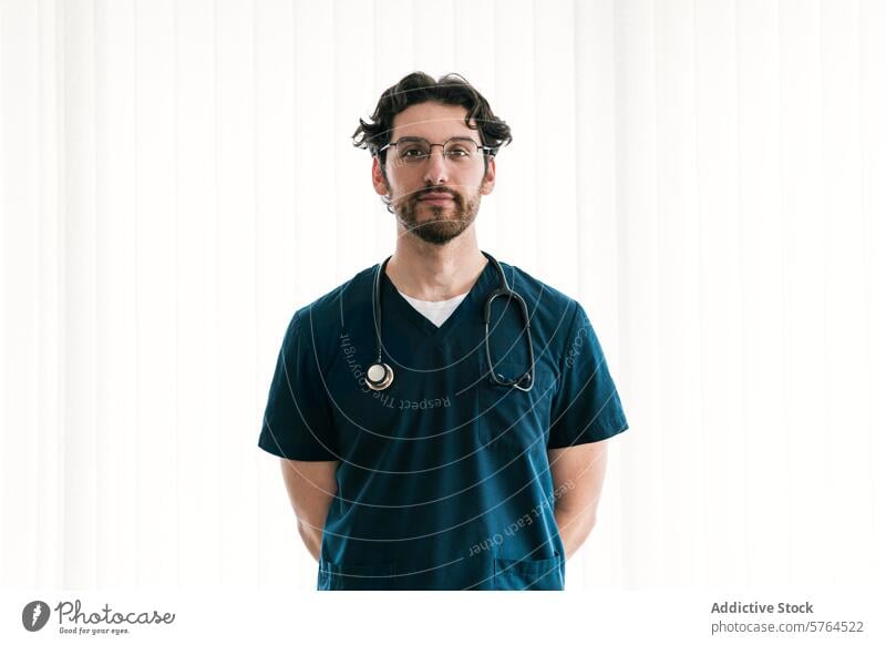 A focused male medical worker in scrubs with a stethoscope stands ready to provide expert care healthcare man professional nurse doctor confident standing duty