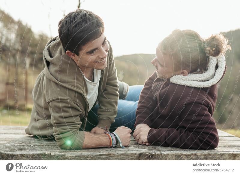 A gay couple enjoys a moment of connection and lighthearted conversation, sitting outside with a backdrop of nature's calm engaged joyful outdoors talking happy