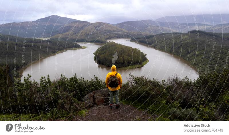 Anonymous hiker overlooking a scenic river meander in winter hill green man landscape nature outdoor journey adventure solitude exploration viewpoint wilderness