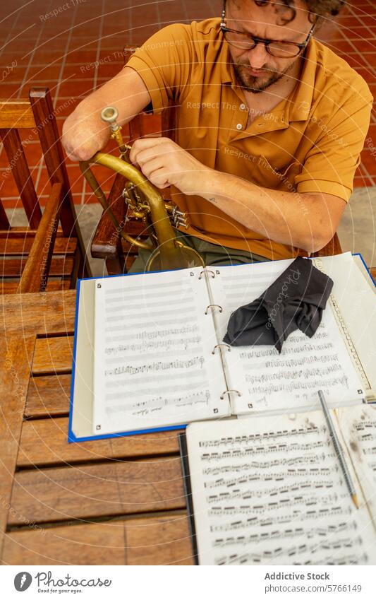 One-armed trumpeter practicing music in his courtyard one-armed musician practice sheet male man creativity outdoors instrument wooden chair glasses