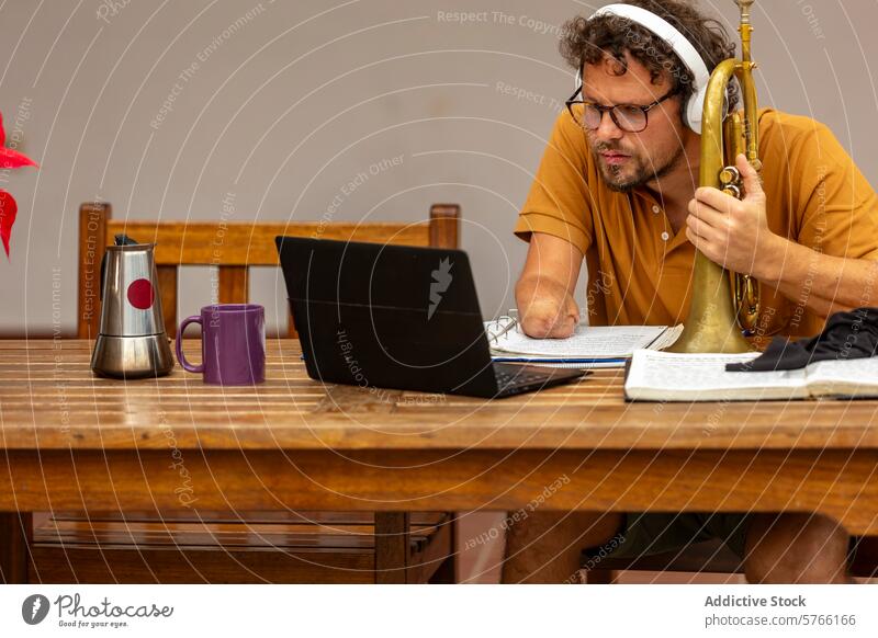 One-armed trumpeter composes music at home courtyard man male one-armed composition creative process work laptop notes focus musician disability adaptation