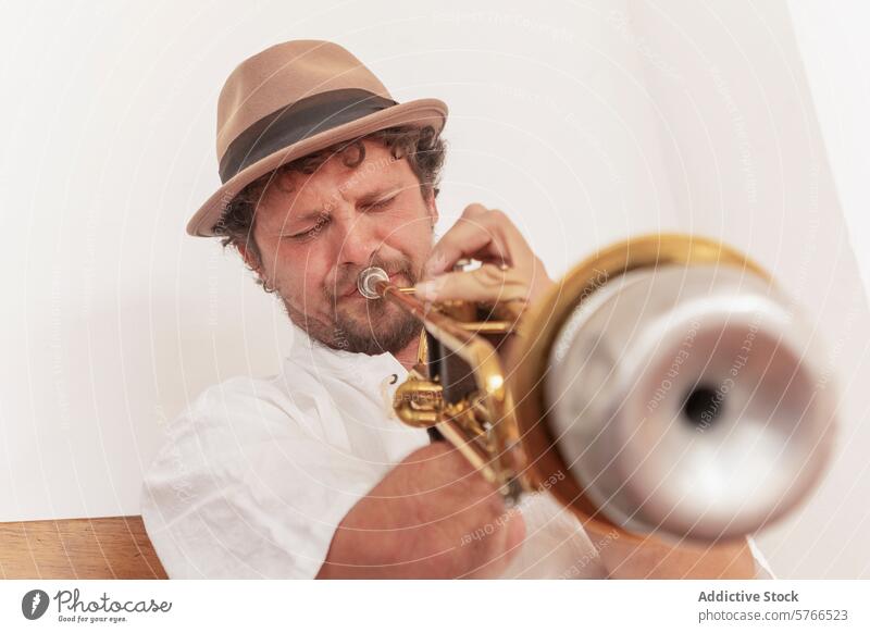 Determined one-armed man practicing trumpet at home trumpeter music practice instrument determination passion brass hat shirt musician disability adaptation