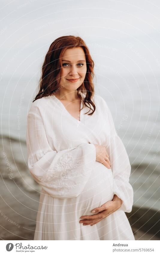 pregnant girl with brown hair on the seashore wife white clothes nearby clay steep cliff mountain water walk sunset light warm summer birds fly forever bride