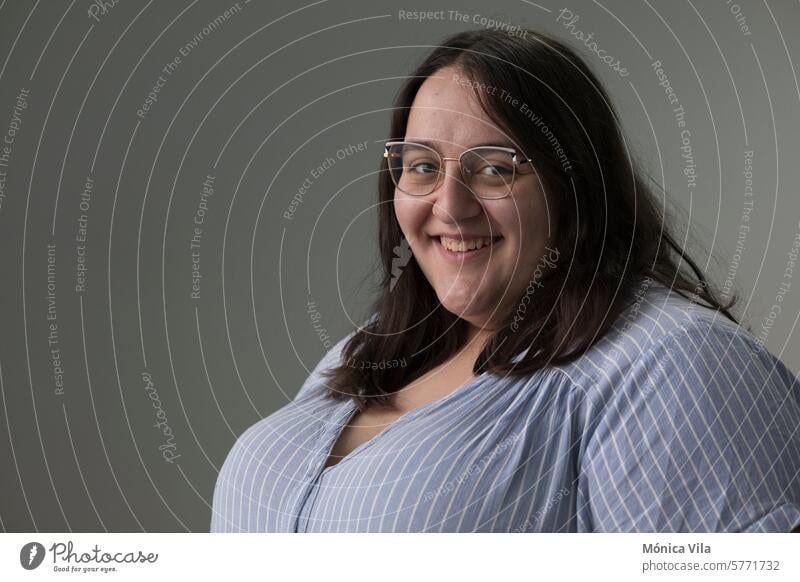 Vertical portrait with soft background of young overweight girl with glasses dressed in striped shirt. Long, brown hair. Smile vertical white background happy