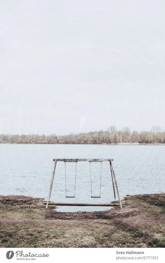 Empty swing in front of the lake Deep depth of field Absence Central perspective straightforwardness relaxation color photograph Concept photo nobody