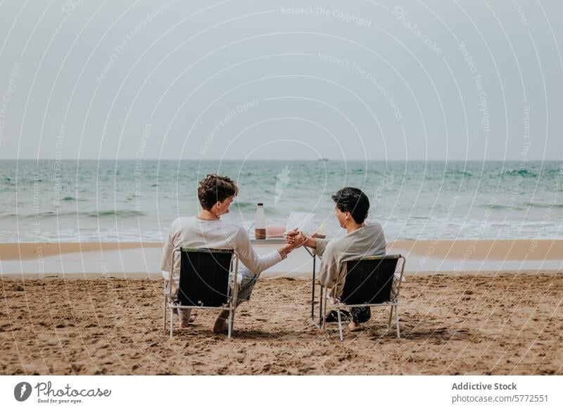 Seaside toasting by friends on a tranquil beach table ocean sand seaside relaxation casual conversation outdoor leisure lifestyle coast shore beverage drink