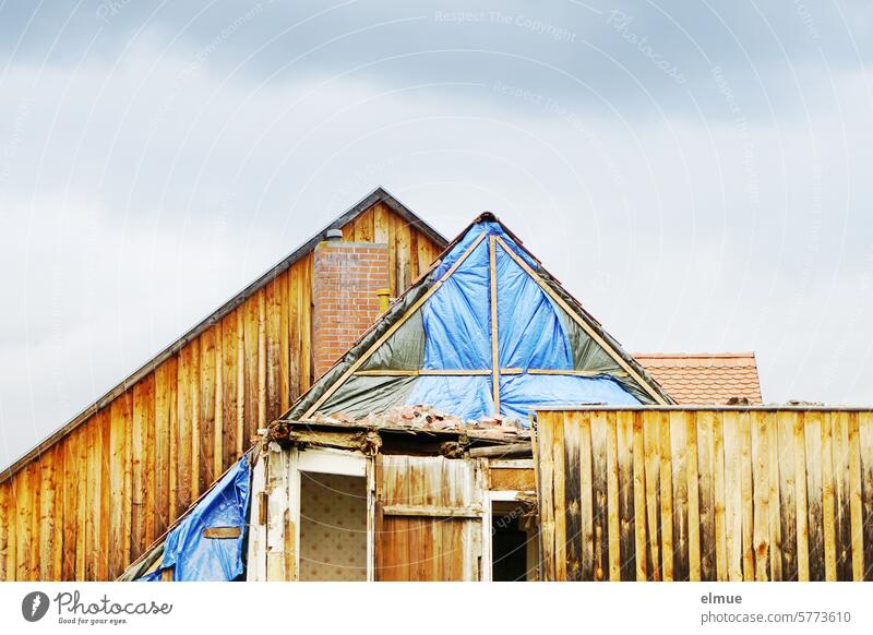 House gable with wooden cladding, partially demolished and covered with a tarpaulin Building for demolition pediment house gables dwell wood panelling Gable