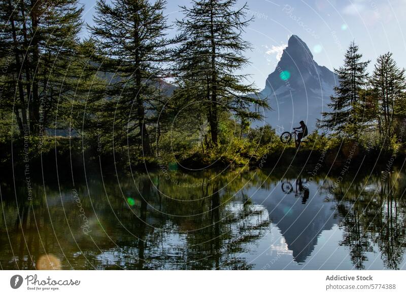 Silhouette biking at serene Matterhorn lakeside silhouette person bike matterhorn reflection water mountain trees calm blue sky alpine scenery outdoor nature