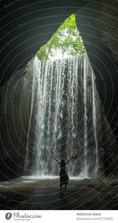 Person standing before a majestic waterfall in Bali person nature bali tropical lush vegetation travel adventure refreshing beauty exotic tranquility calm