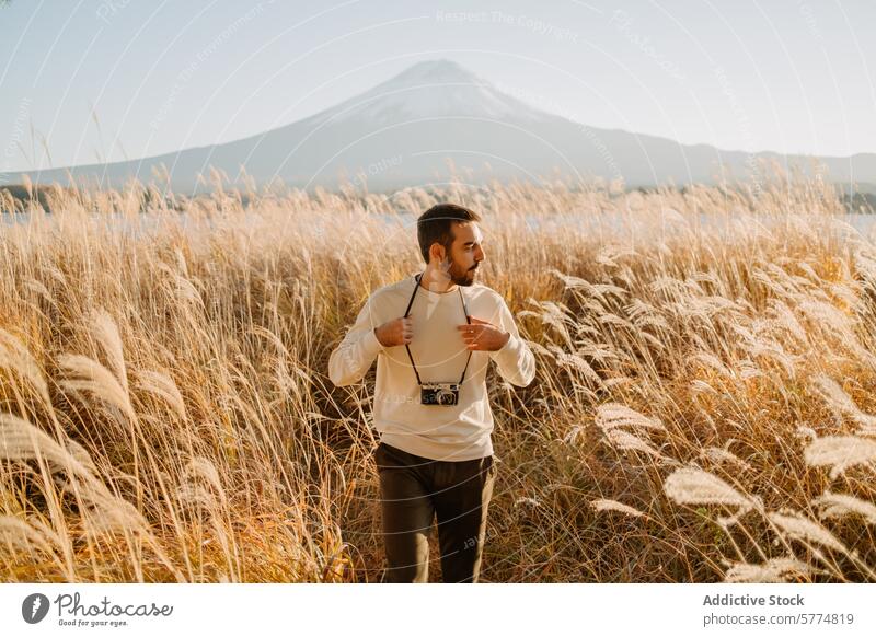 Exploring Japan, Man with camera against Mount Fuji traveler japan mount fuji exploration majestic view pampas grass clear sky adventure tourist nature