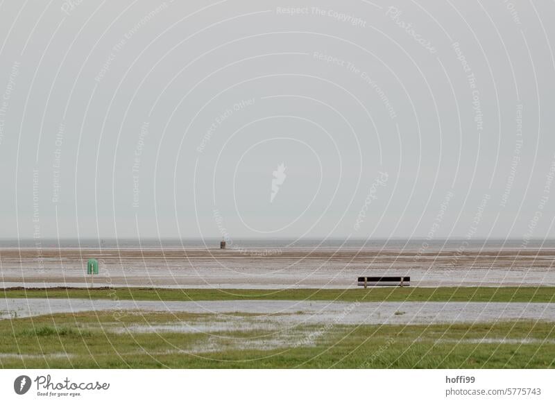 Minimalist scene on the North Sea with bench, garbage can and flooded sunbathing lawn North Sea coast Ocean Deluge Bad weather High tide Rain after the rain