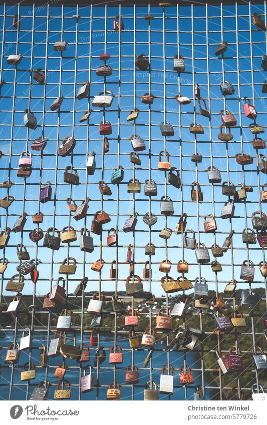 Love locks on a metal grid with water and blue sky in the background Padlocks Infatuation Kitsch Symbols and metaphors Sympathy Wedding oath relation