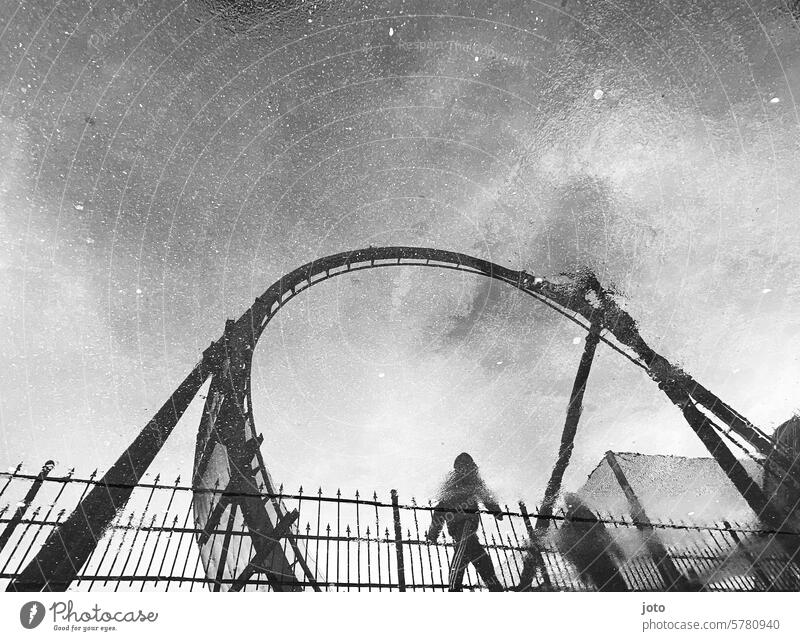 Reflection of a roller coaster and two people in a puddle on a rainy day Umbrella Roller coaster Puddle reflection Reflection in the water rainy weather Autumn