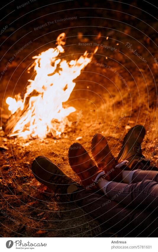 Young couple a guy and a girl in bright knitted hats stopped at a camping young beard warmth tent bonfire love get warm drink tea firewood blue orange cage