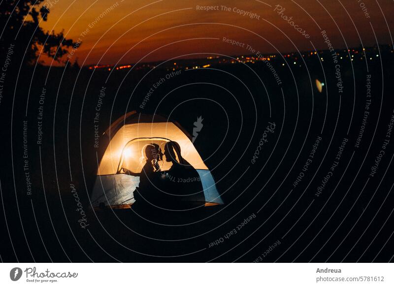 Young couple a guy and a girl in bright knitted hats stopped at a camping young beard warmth tent bonfire love get warm drink tea firewood blue orange cage