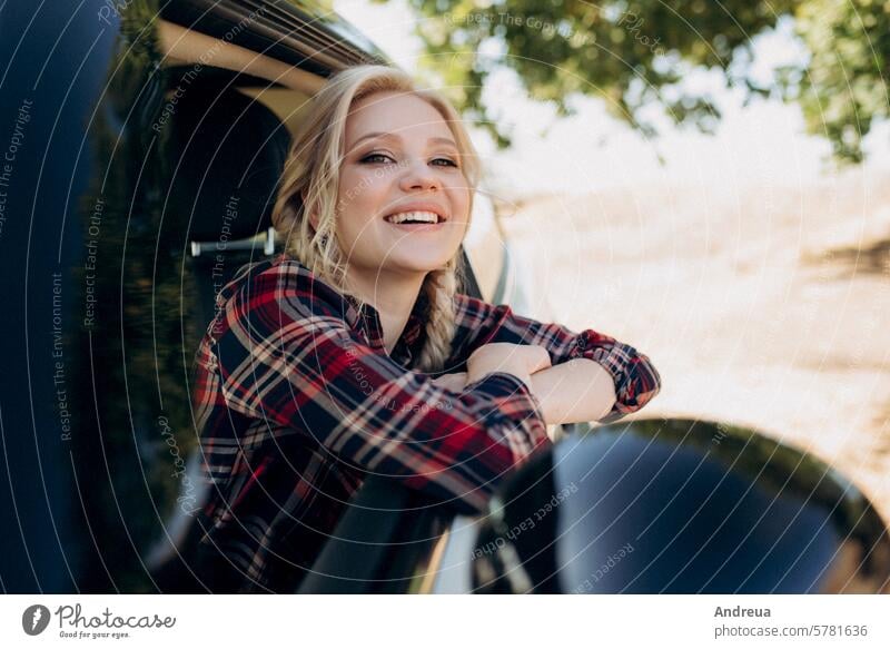 blonde with pigtails in a shirt, jeans, red shoes and black glasses autumn blue brown car checkered clothing earth grass girl into the distance look modern