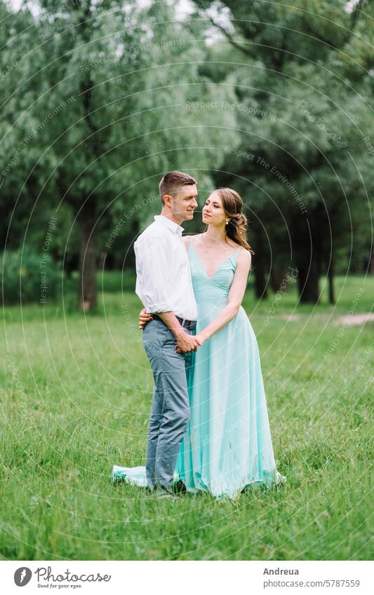 happy guy in a white shirt and a girl in a turquoise dress are walking in the forest park young grass trees bushes green brown day summer spring love nature