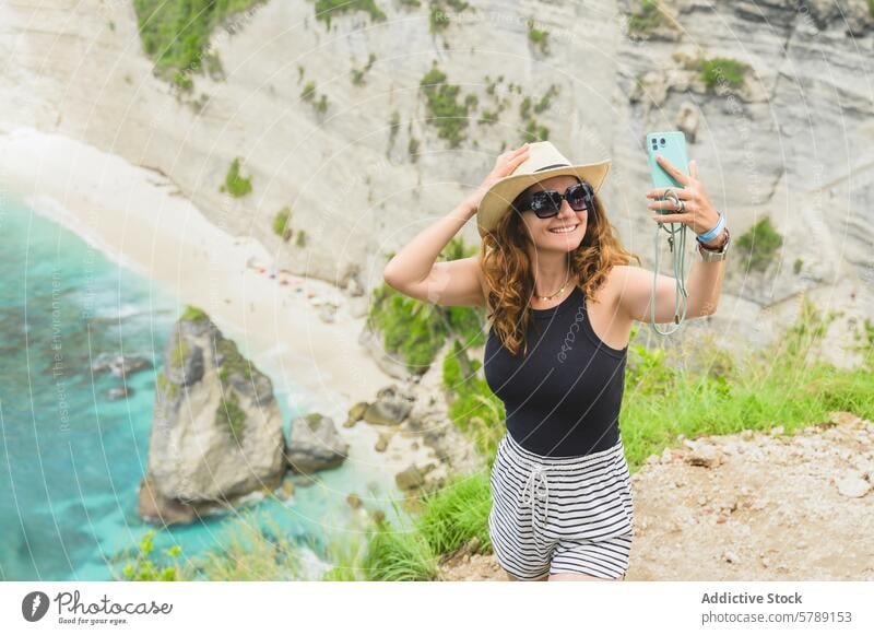 Tourist capturing a selfie at Nusa Penida, Bali tourist nusa penida bali woman travel vacation mobile phone photography coast cliff beach ocean nature tropical