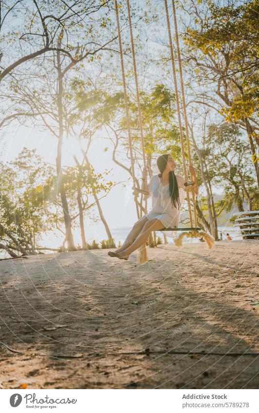 Sunlit swing relaxation in Costa Rica woman costa rica sunlight trees serenity peace calm tranquil beach nature outdoor tropical serene leisure vacation travel