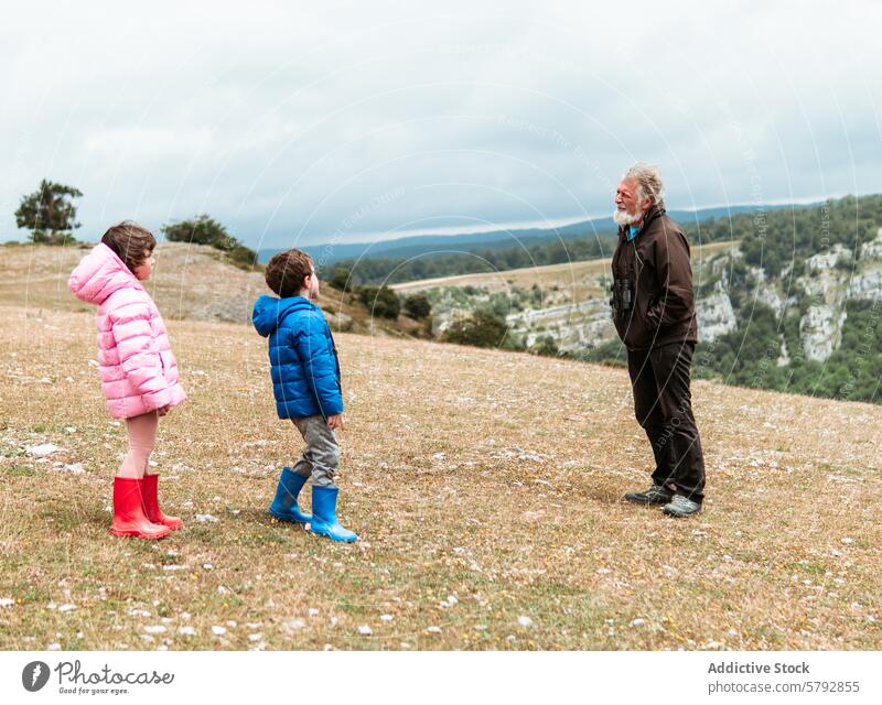 Grandfather with grandchildren enjoying nature together grandfather boy girl family leisure outdoor hill grassy bonding field scenic view landscape adventure