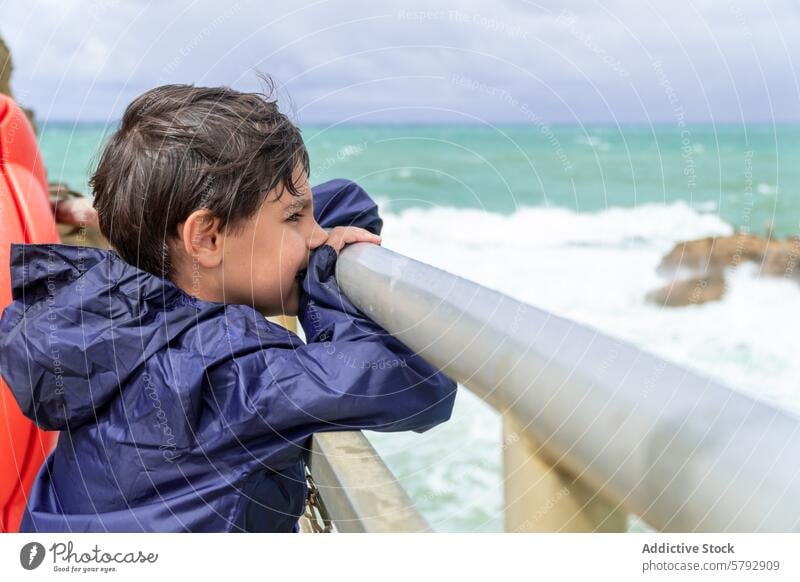 Contemplative child gazing at sea from French pier boy waves coast capbreton france raincoat blue contemplative shore ocean railing crash kid rock nature