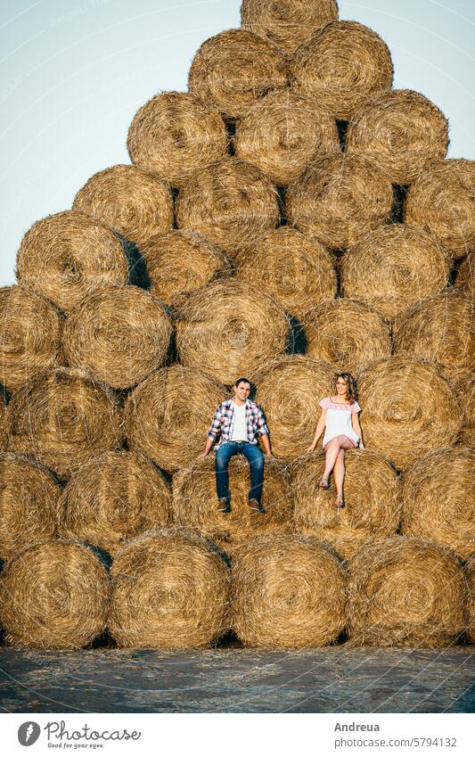 a guy with a girl on a summer walk in the field round haystack dry yellow dress shirt cage drawing pattern warehouse mountain sunset evening village farmer