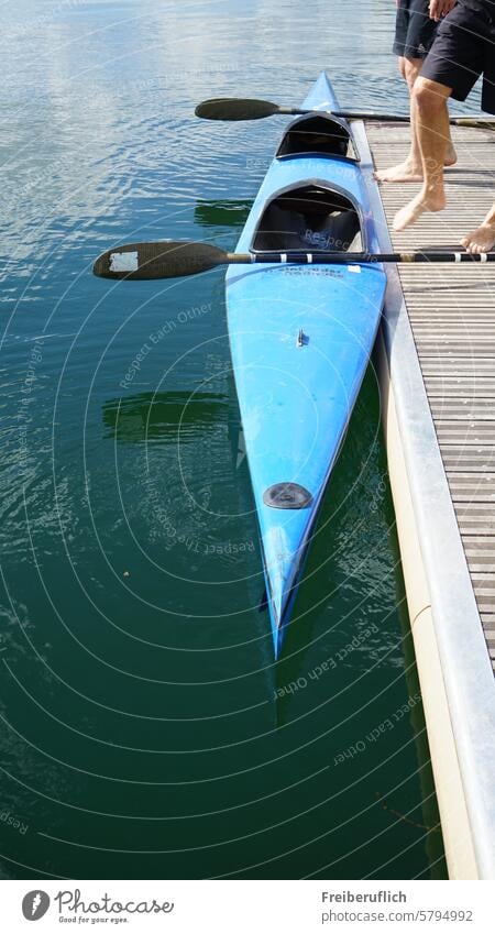 Racing boat kayak two-seater with paddle at the jetty, two athletes getting in Canoe Racing sports Kayak Two Canoe racing Blue Water Trip on the river