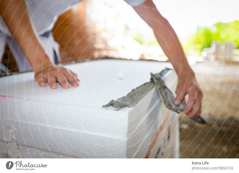 Worker applies the glue to thermal isolation material, styrofoam with spatula Adhesive Affix Apply Applying Attach Building Site Cement Civil Engineering