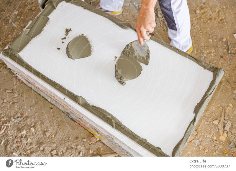 Worker applies the glue to thermal isolation material, styrofoam with spatula Adhesive Affix Apply Applying Attach Building Site Cement Civil Engineering