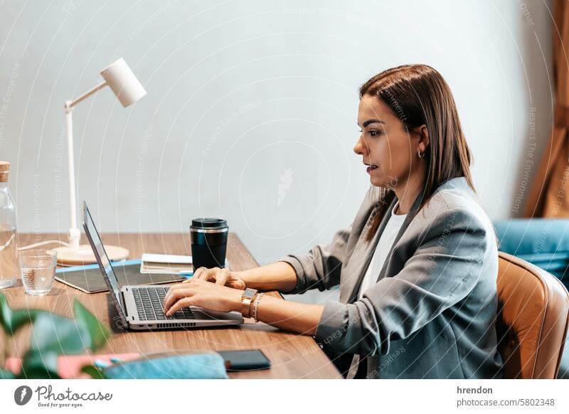 woman working in an office typing on the laptop businesswoman using indoor focused cyberspace entrepreneur technology professional connection manager success