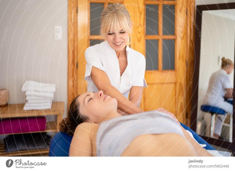 Content female physiotherapist treating neck of patient women osteopath manual therapy osteopathy stretch manipulation appointment touch head touch shoulder