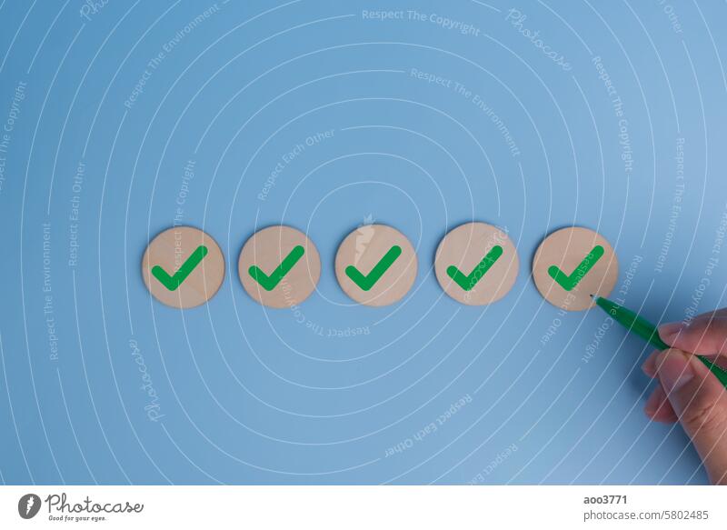 hand holding pen check mark on blue background. Business quality target strategy marketing concept. wood work success idea checklist project control business