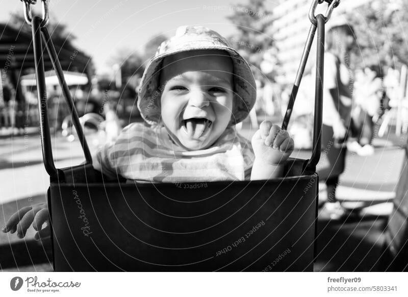 Portrait of a nine month old baby having fun on a swing toddler park happiness funny happy boy play school preschool recreation day care cheerful spring