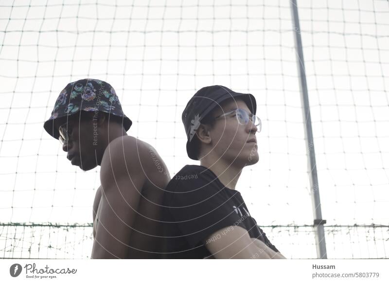 photo of two friends wearing hats and posing back to back in playground background people isolated fashion nature concept health happy sunset lifestyle park