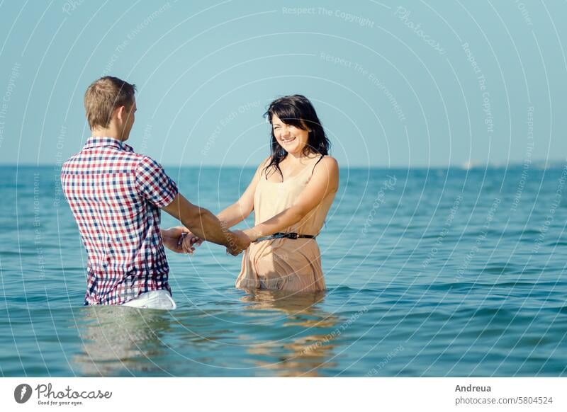 a guy and a girl walk along the seashore on the shore water joy smiles together blue sky beach sand love couple summer cool coast barefoot lie down wet