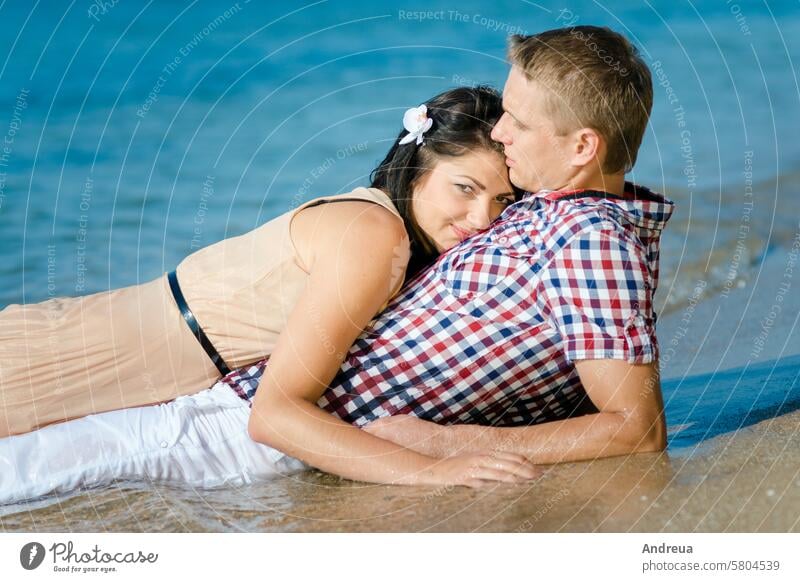 a guy and a girl walk along the seashore on the shore water joy smiles together blue sky beach sand love couple summer cool coast barefoot lie down wet