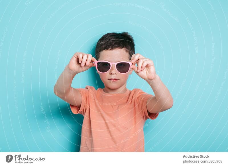 Young boy with sunglasses on turquoise background kid school child youth cool style confident stare camera portrait fashion accessory personality individuality