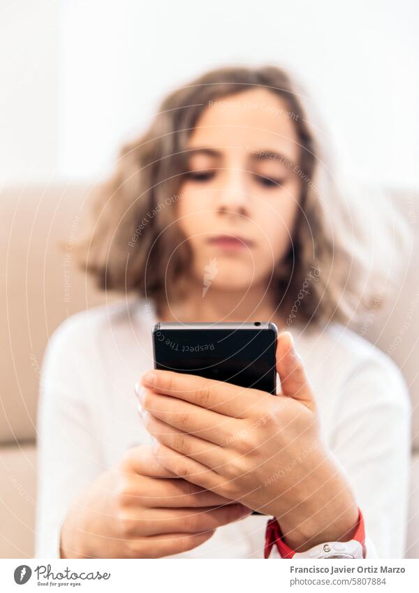 Young Girl Relaxing on Couch with Smartphone girl smartphone couch sitting home indoor technology mobile communication screen texting browsing social media