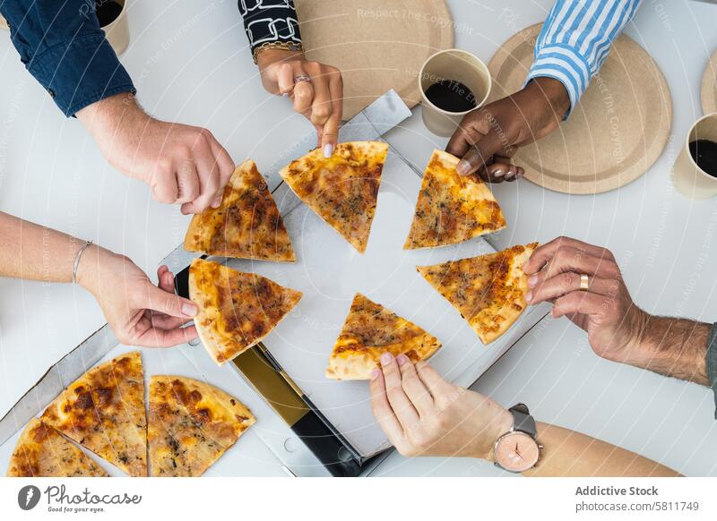 Crop diverse friends eating pizza during meeting table company gather tablet piece group friendship multiethnic multiracial food together delicious tasty meal