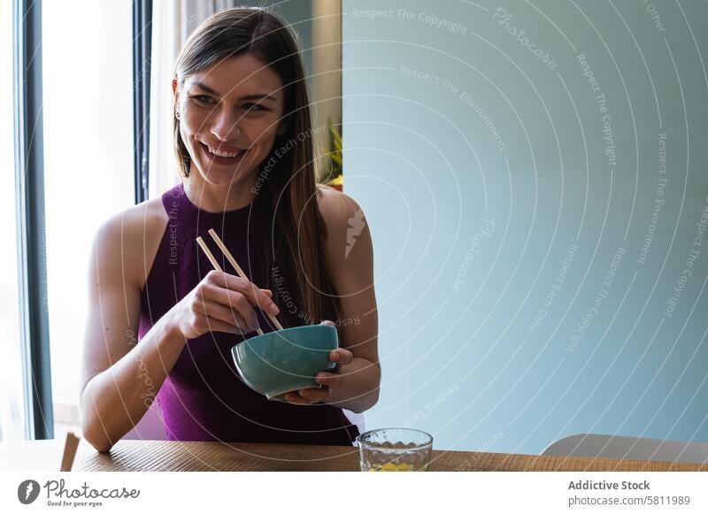 Cheerful woman with chopsticks having lunch in dining room eat food happy toothy smile delicious enjoy meal asian food hungry appetite lifestyle content